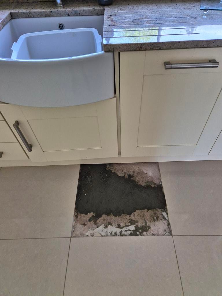 A kitchen floor tile lifted beneath sink units